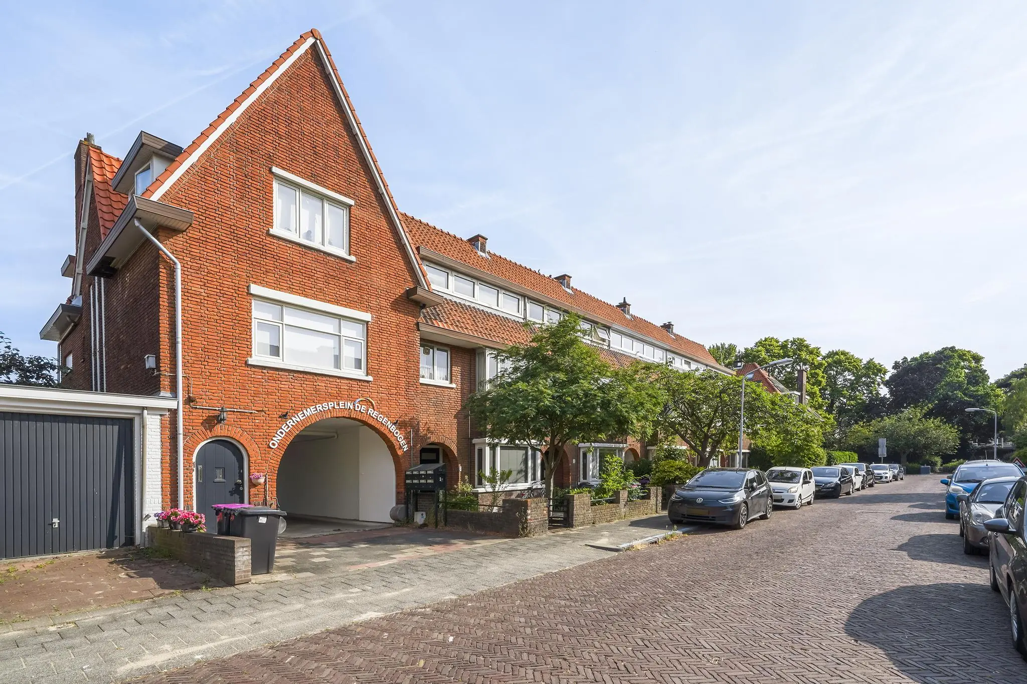 Rij stijlvol gerenoveerde jaren-'30 woningen aan de Jacques Perkstraat met zicht op Ondernemersplein De Regenboog.